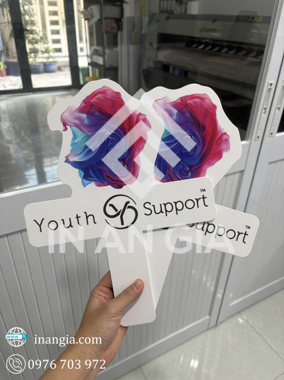 Biển cầm tay Youth Support in logo và họa tiết màu sắc, cầm trên tay trong xưởng in