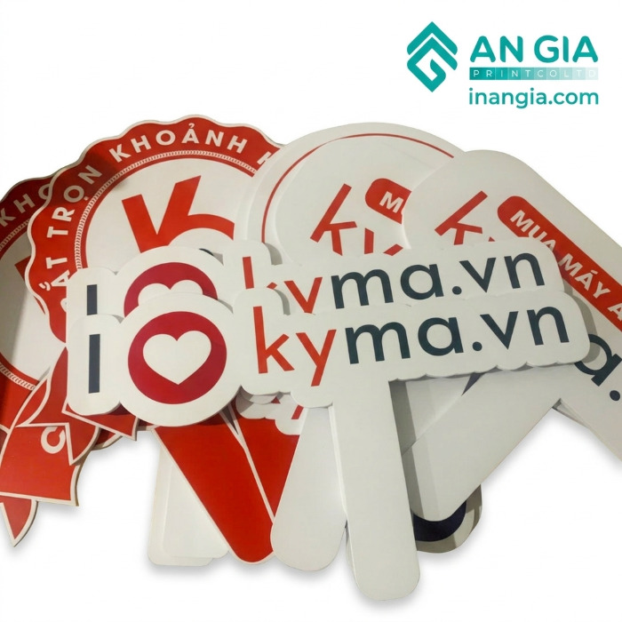 Biển cầm tay quảng cáo in logo kyma.vn và các slogan đỏ trắng của công ty in ấn An Gia