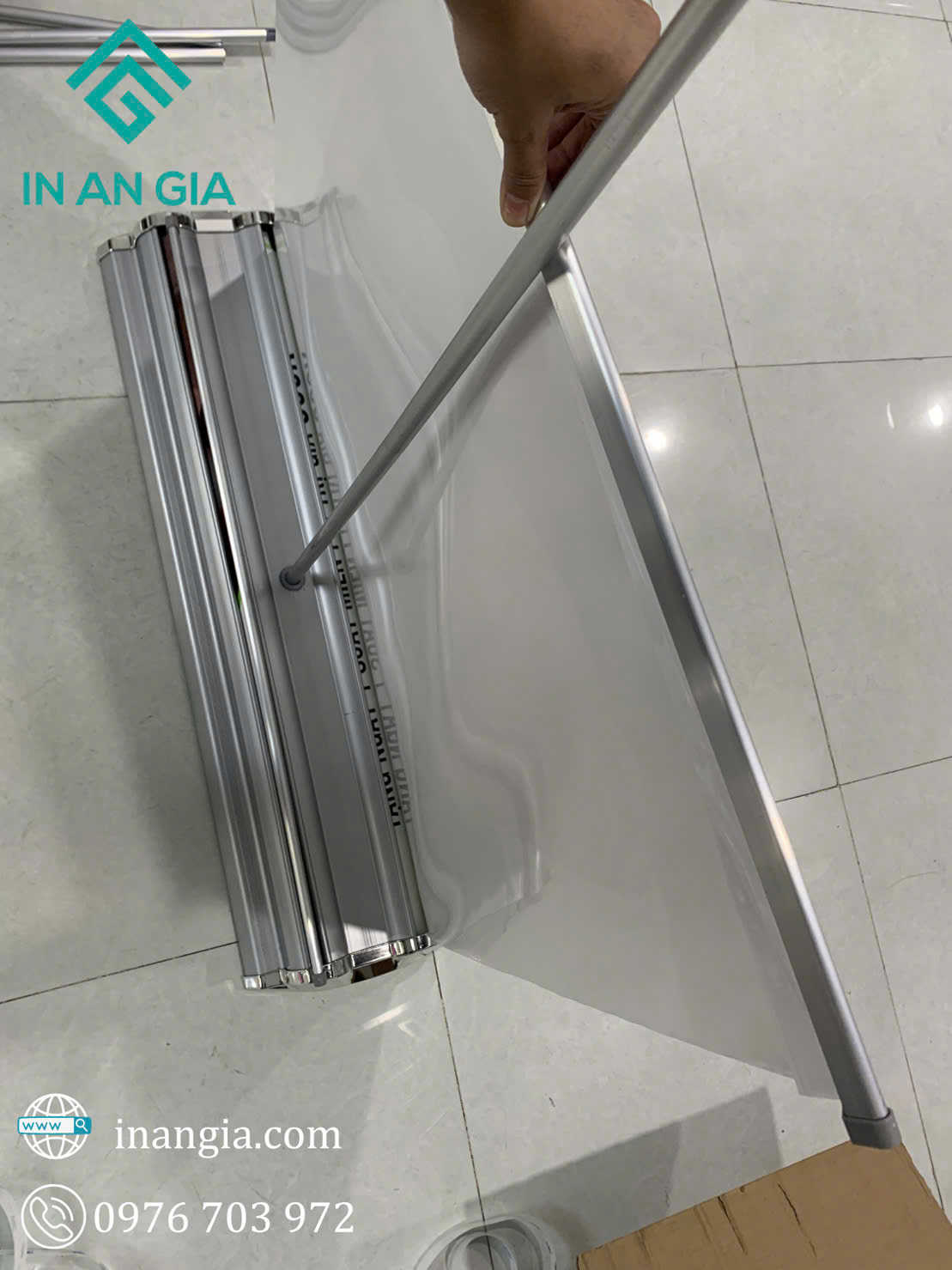 Lắp đặt standee cuốn nhôm In An Gia với người dùng đang kéo căng bạt quảng cáo